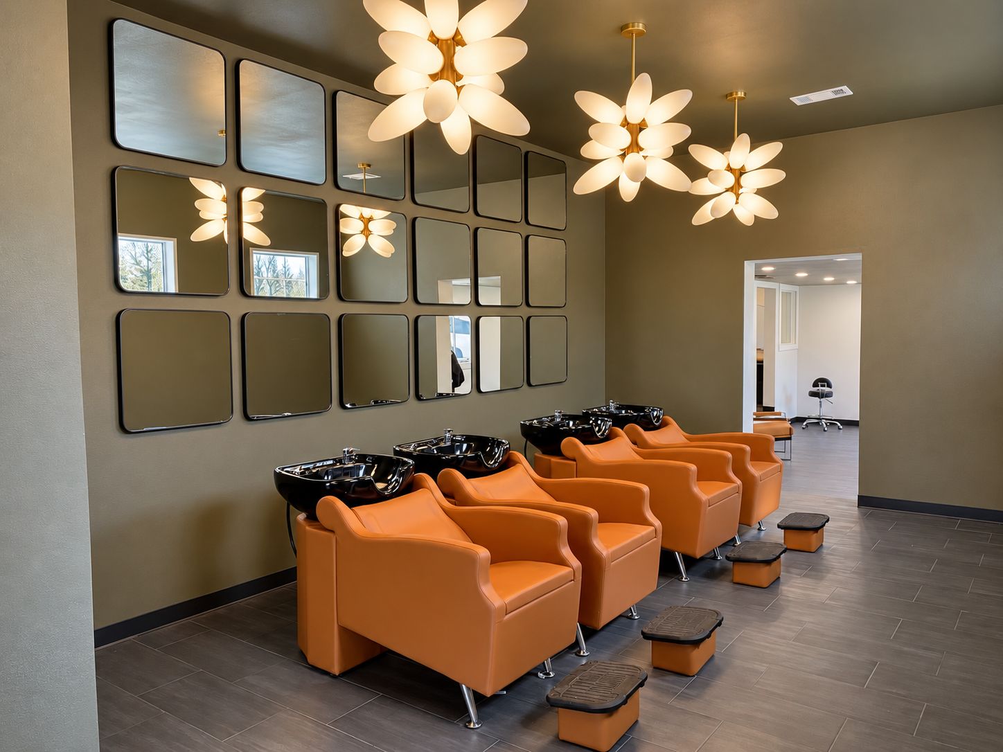 The shampoo room, with four cognac leather backwash chairs under floral pendant lights
